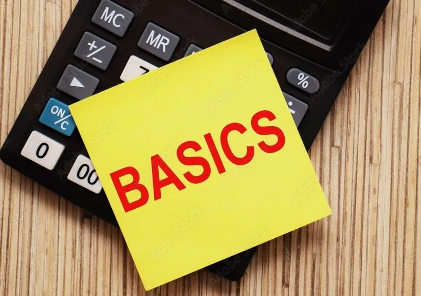 Calculator with a yellow sticky note reading 'BASICS' on top, placed on a wooden surface. BASIC TAX RETURN