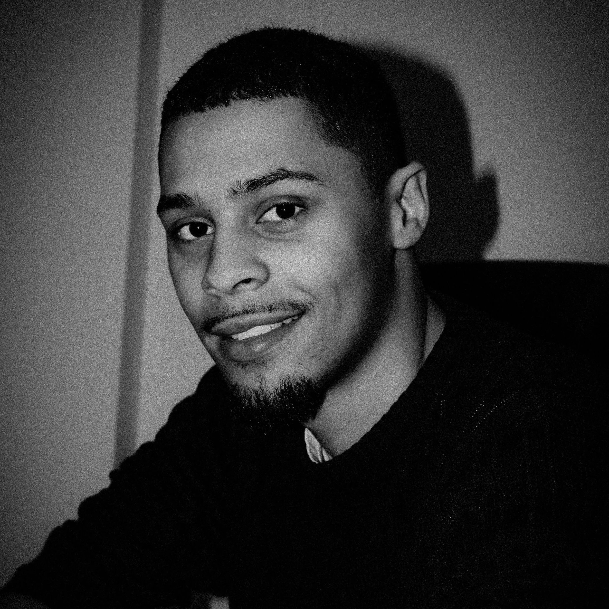 A person wearing a dark jumper, posing for a camera