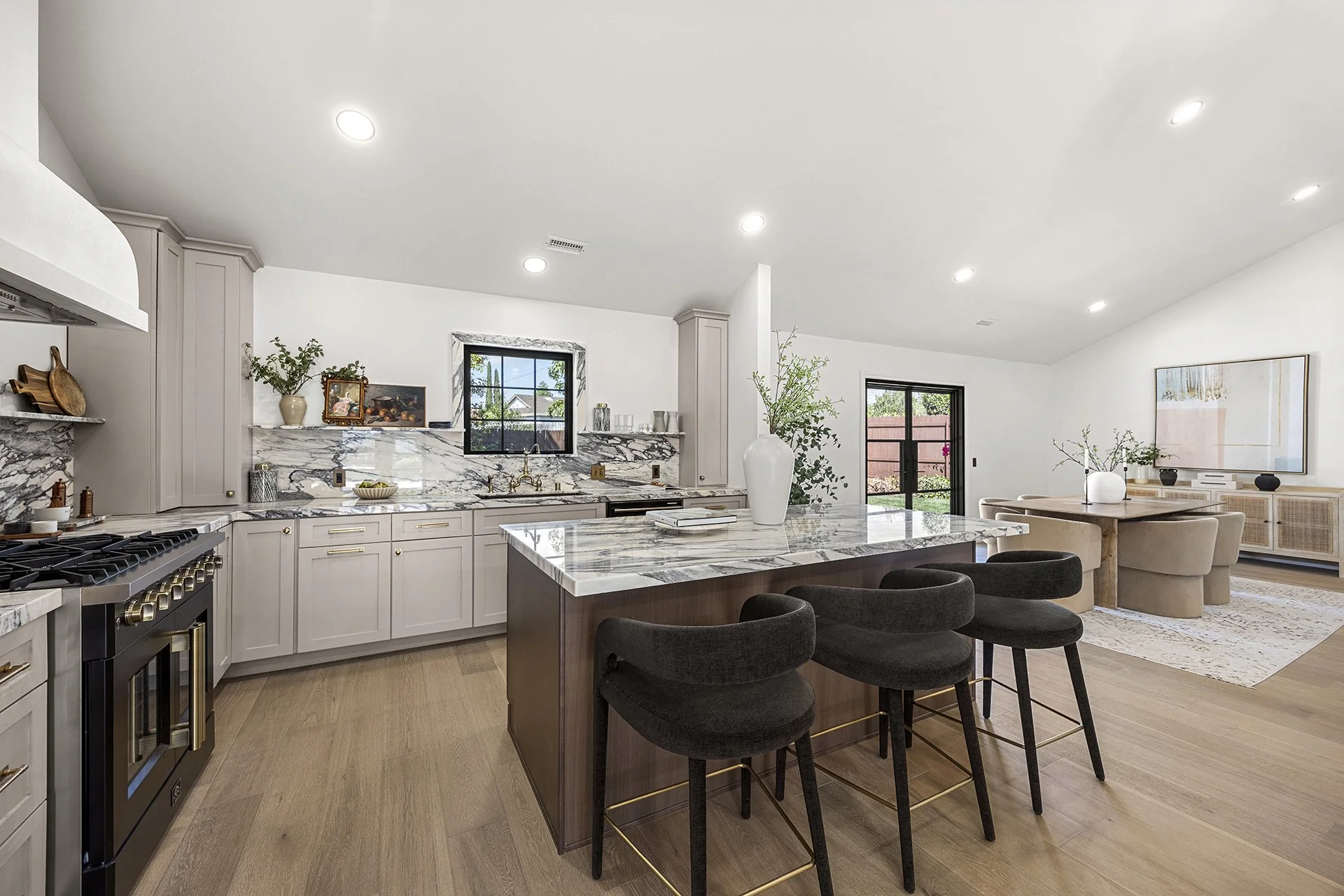 3D rendering of a modern kitchen with black appliances, white cabinetry, a wooden table, and a window on the wall.