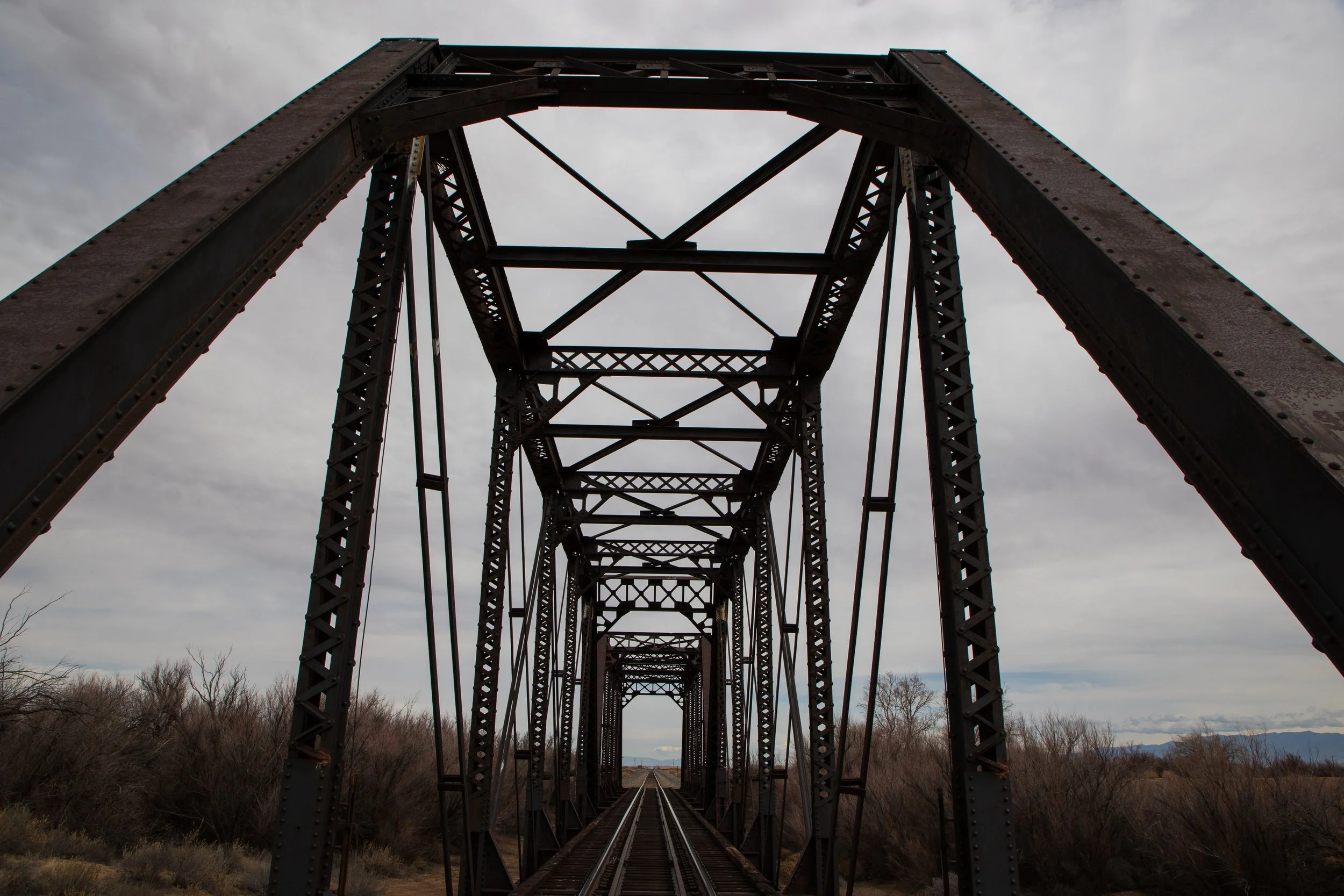 Vintage steel railway bridge with tracks, cloudy sky background
