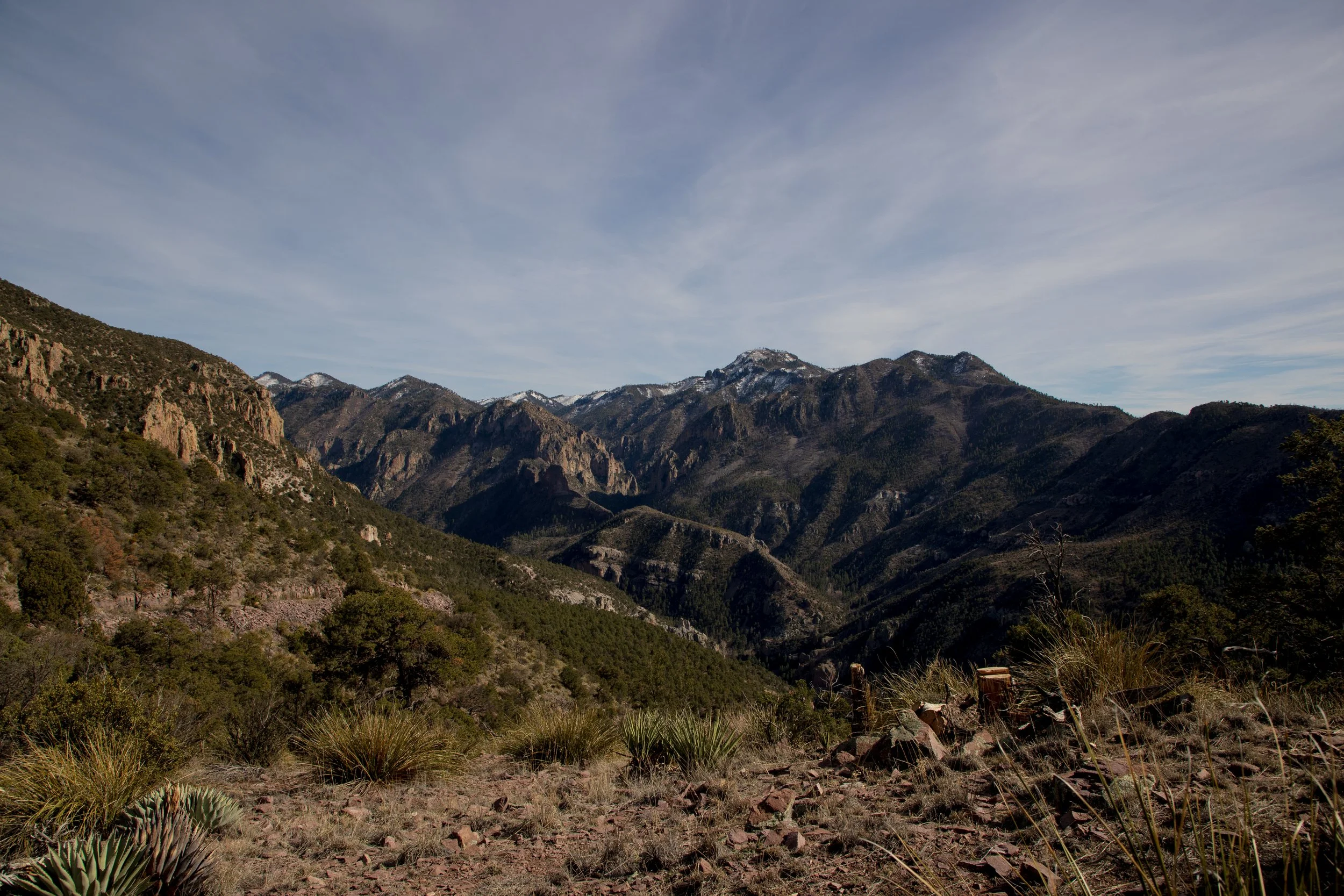 Mountain landscape with rocky terrains and sparse vegetation under a clear sky.