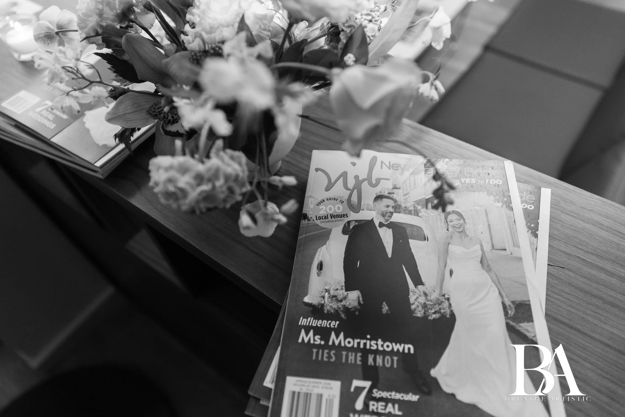 Wedding magazine titled "Digi" featuring a bride and groom on the cover, placed on a wooden table next to a flower arrangement and other magazines.
