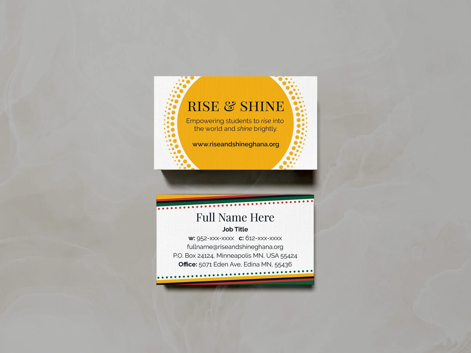 Two business cards on a gray surface promoting the non-profit organization Rise & Shine, one with a yellow and white sunshine design the other with a white background and colorful Ghana-inspired border containing contact information.