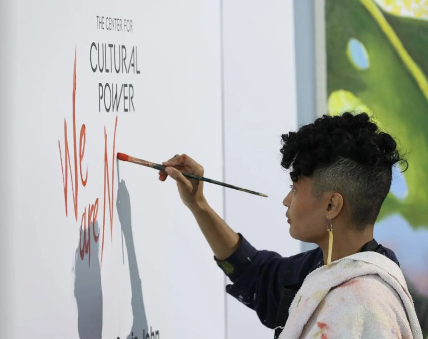Artist Sonja John titles the power mural by hand during a joyful dedication ceremony, a distinctive event in the center of the conference schedule.