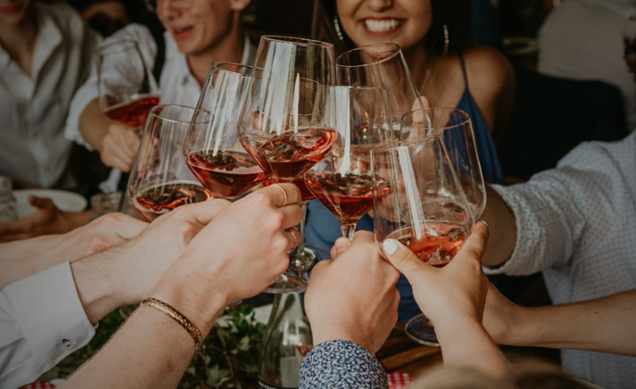People raising glasses of rosé wine for a toast at a celebration.