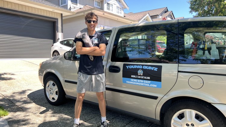 Logan, founder of Young Gun'z Mobile Detailing, beside the branded van
