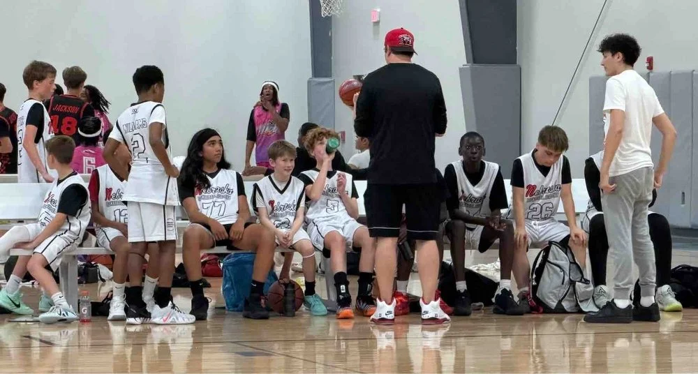 Nebraska Basketball Academy boys team on the bench listening to their head coach during halftime