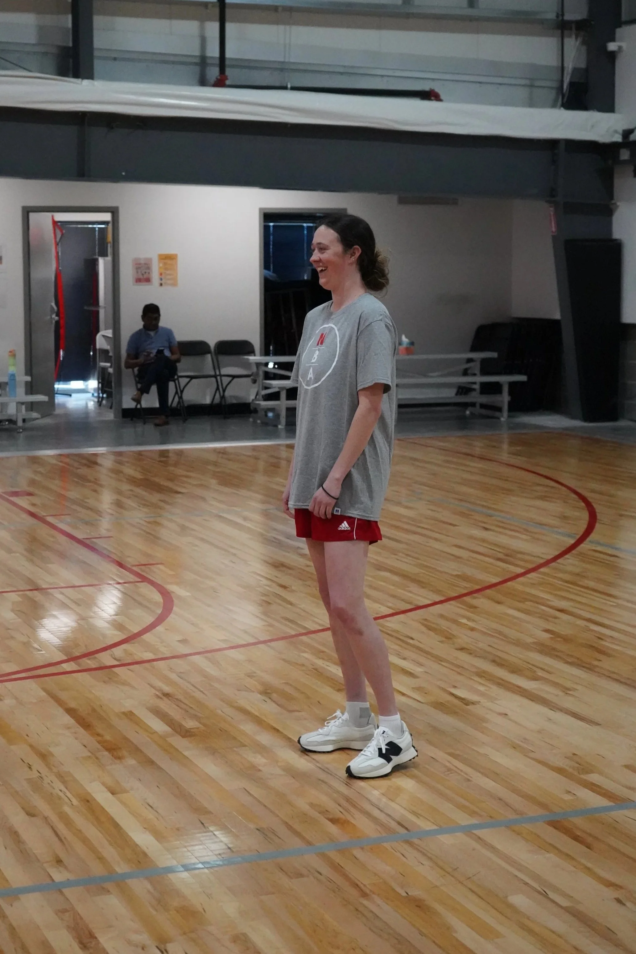 Woman in Nebraska Basketball Academy shirt smiling and coaching