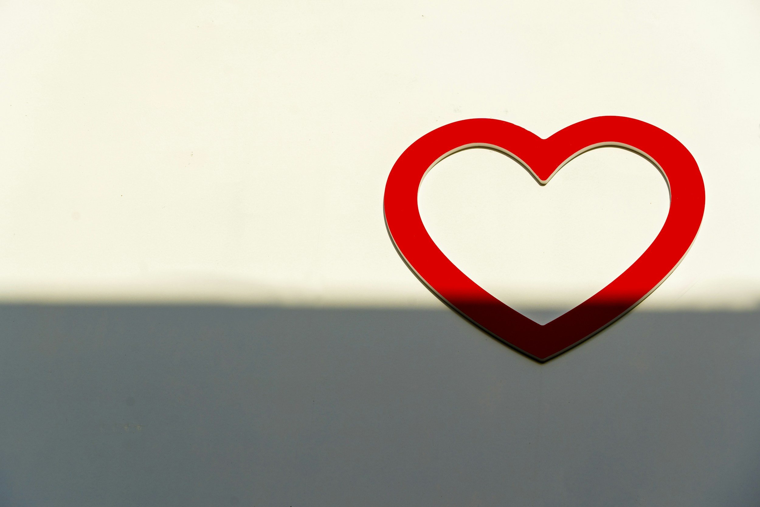 Red heart-shaped frame on a white and gray background with soft shadow.