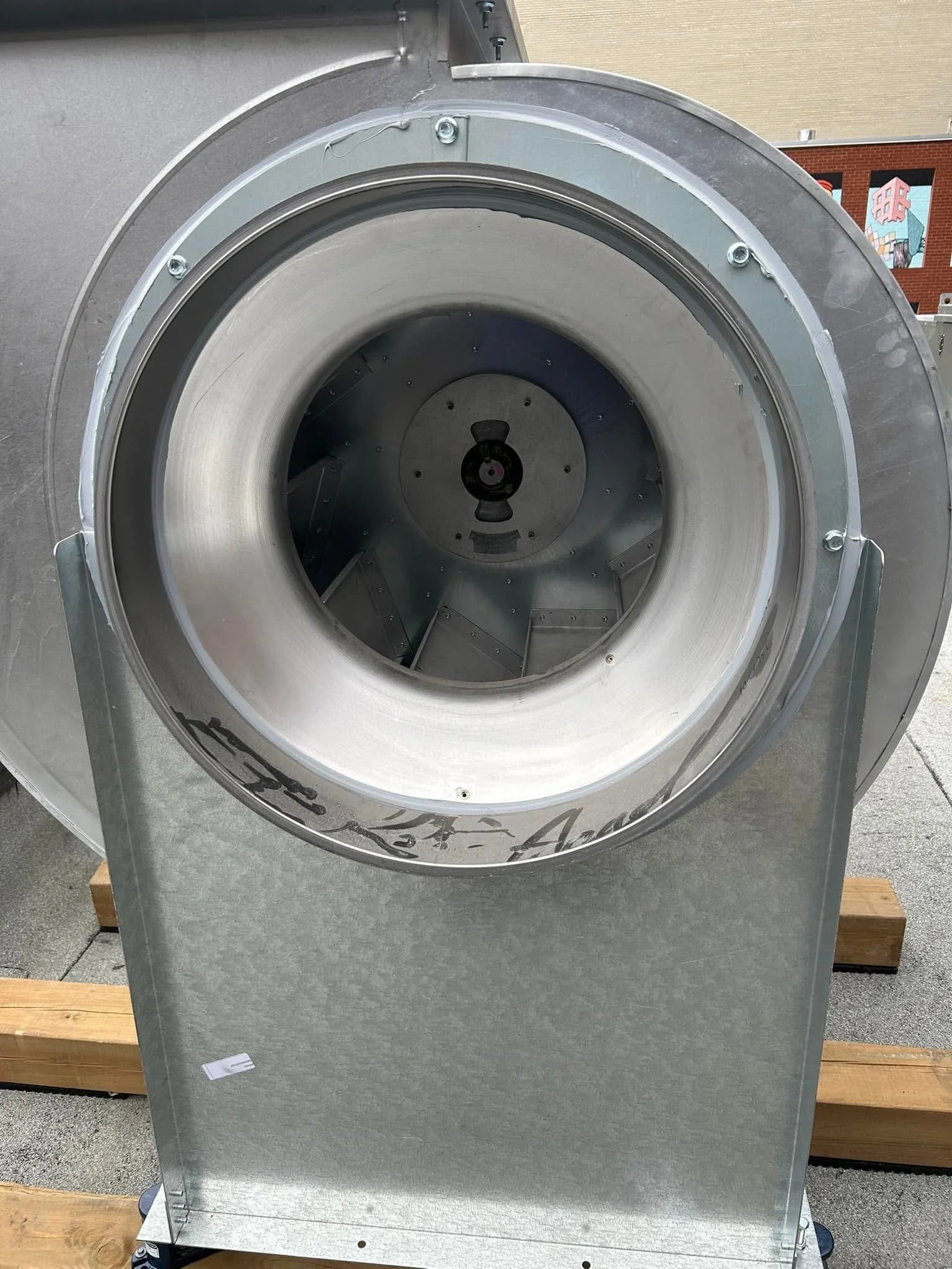 Ventilateur industriel métallique sur une palette en bois.