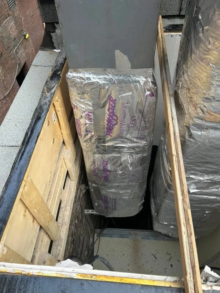 Des matériaux de construction isolés entre des panneaux de bois dans un espace restreint sur un toit.