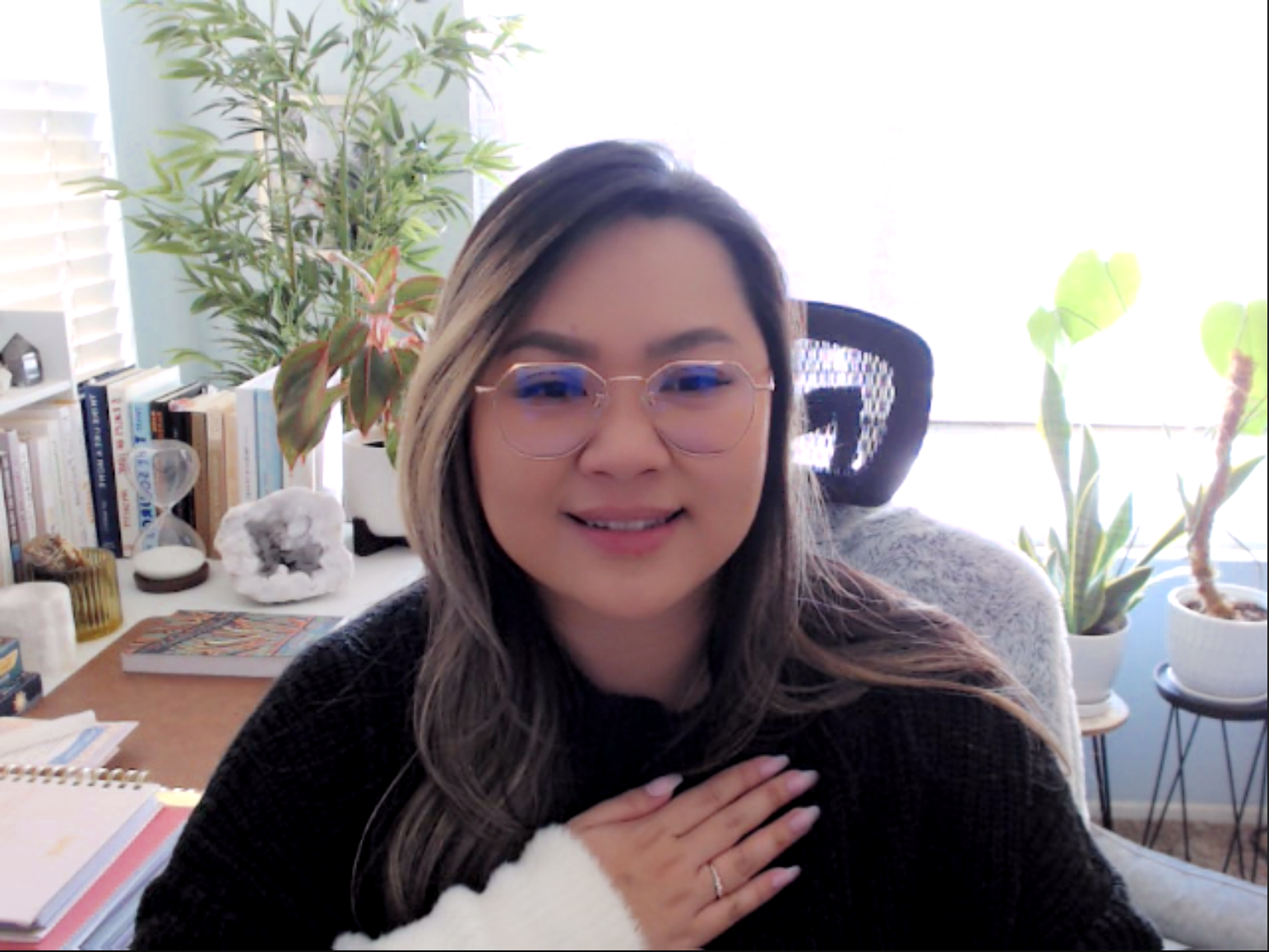 Person sitting at a desk with potted plants, books, and a decorative geode in the background.