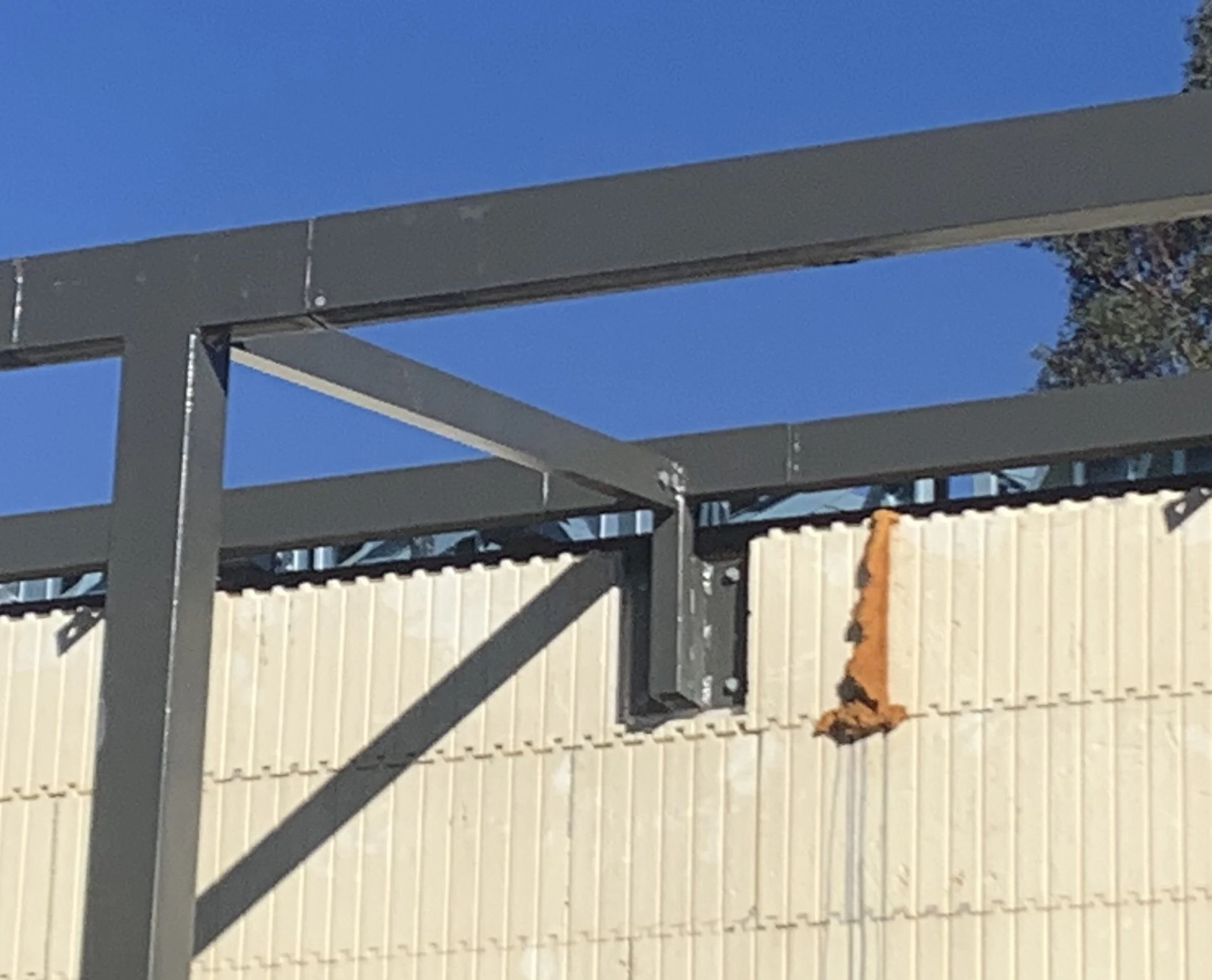 Close-up of a bespoke steel beam verandah structure against a blue sky, with a section of wall made from insulated concrete forms (ICFs) for a passive home.