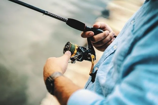 Close-up of a man's hands adjusting a fishing reel, representing the steadiness that comes once a habit is actually resolved instead of just promised away again.