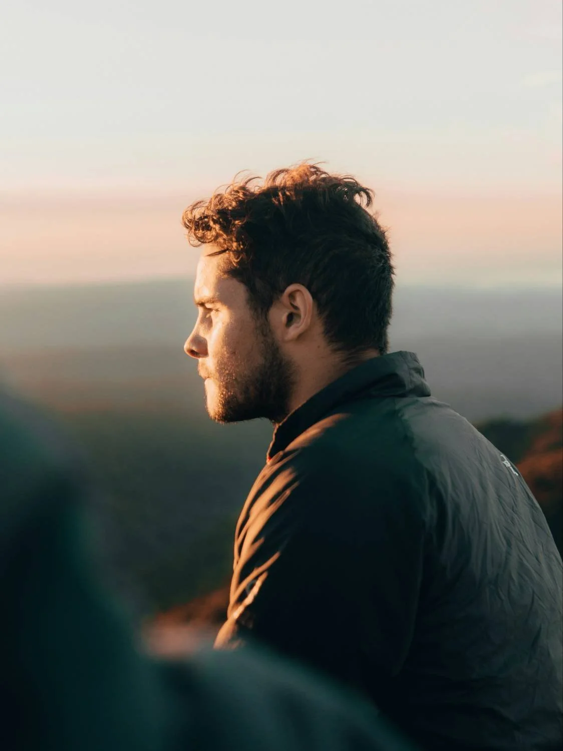 Young bearded man in profile outdoors at elevation, representing anxiety hidden by Christian talk in faith-based counseling for men.