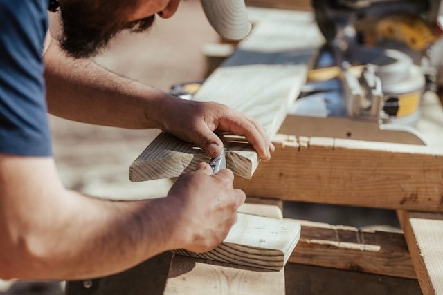Bearded man working with wood at an outdoor workbench, representing a faith-informed therapist who shares his clients' beliefs.