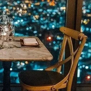 A table set for two overlooking a city skyline at night, representing the same date patterns that keep single men stuck when dating and relationship struggles go unaddressed.