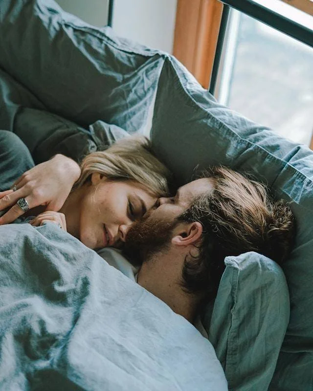 Man and woman lying close together in bed, representing relationship patterns addressed in men's anxiety counseling.