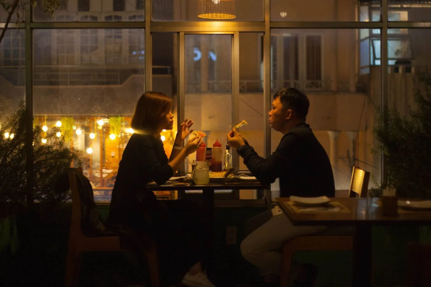 Man and woman eating at a restaurant table at night, illustrating secure attachment and relationship presence for men in Mooresville, NC.