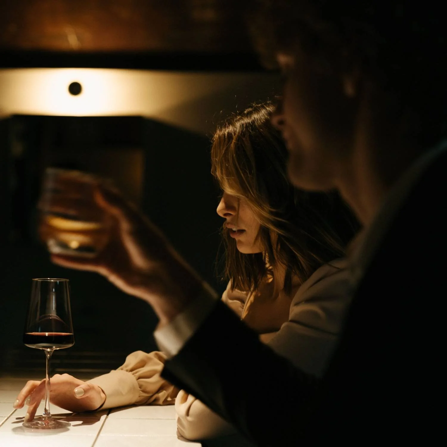Man and woman sitting at a bar with wine glasses, illustrating avoidant attachment patterns in men's relationship therapy.