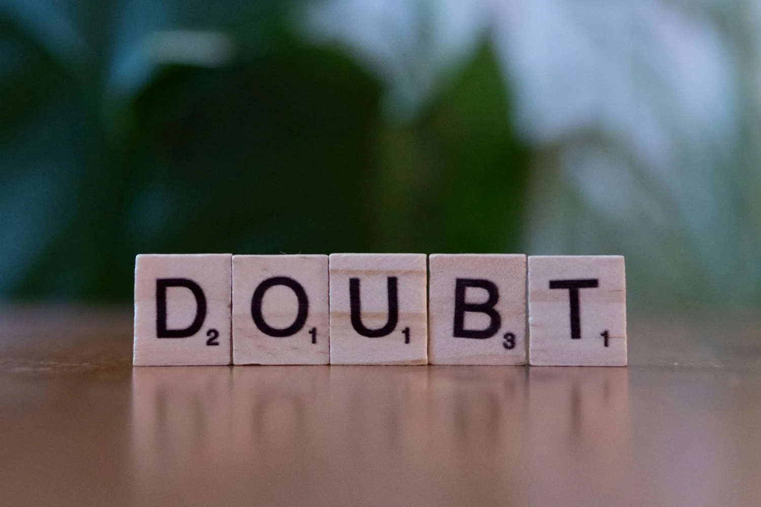 Scrabble tiles spelling DOUBT on a wooden surface, representing obsessive doubt in scrupulosity and religious OCD.