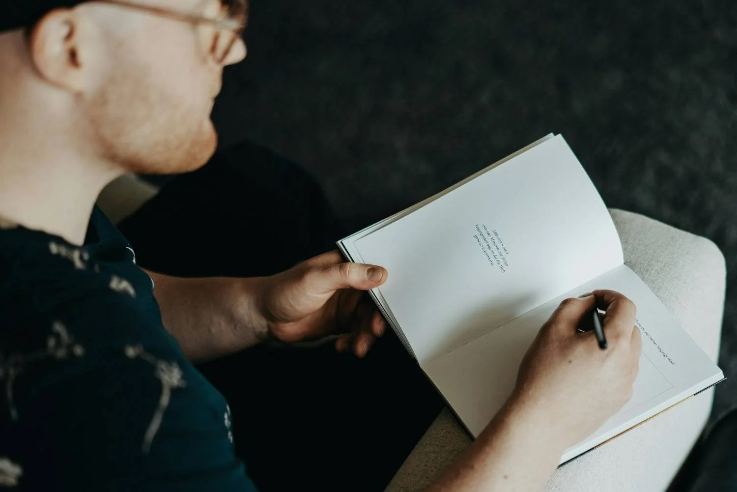 Man with glasses writing in an open notebook on a chair, individual relationship therapy session in Mooresville, NC.