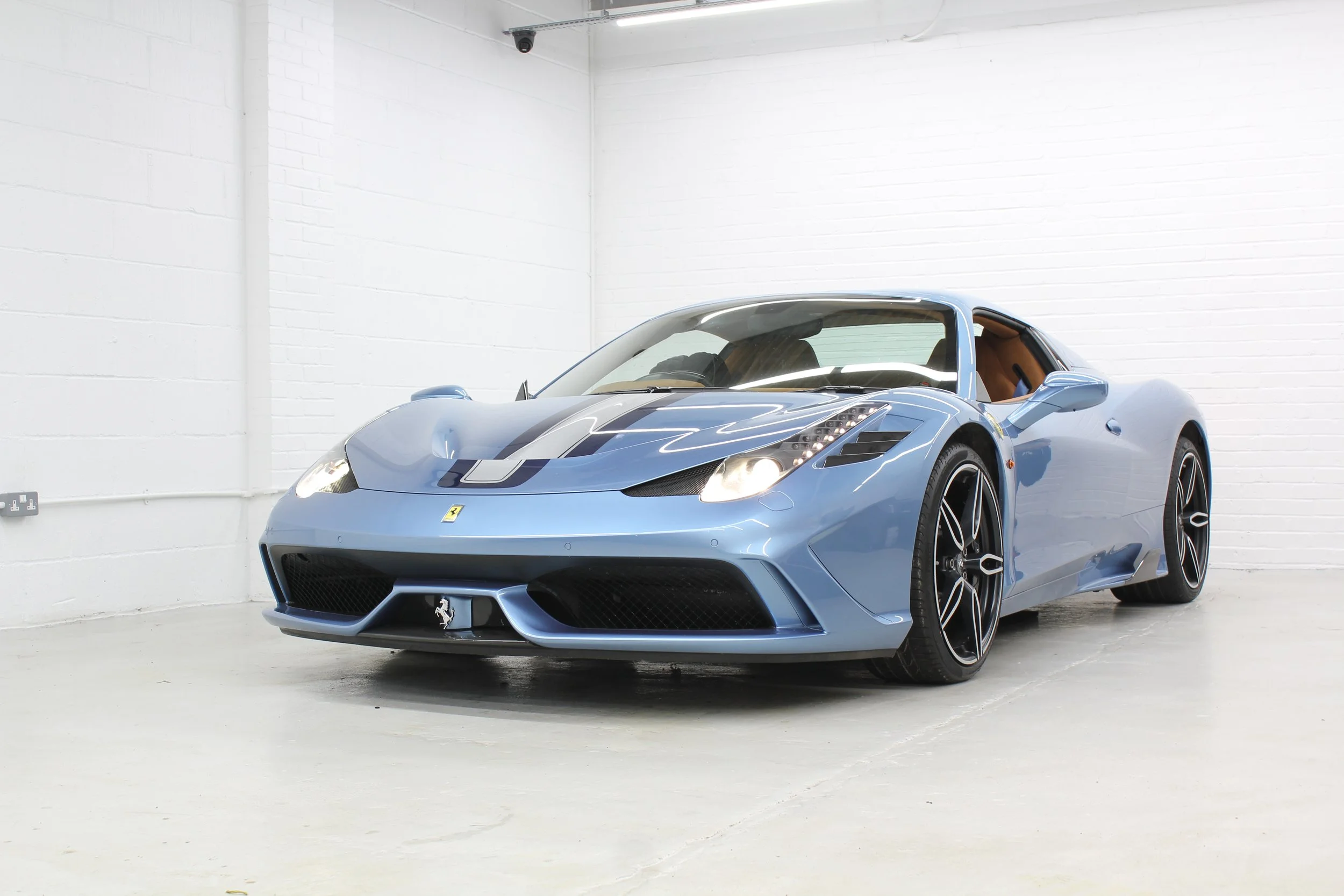 Light blue Ferrari sports car parked indoors in a white room