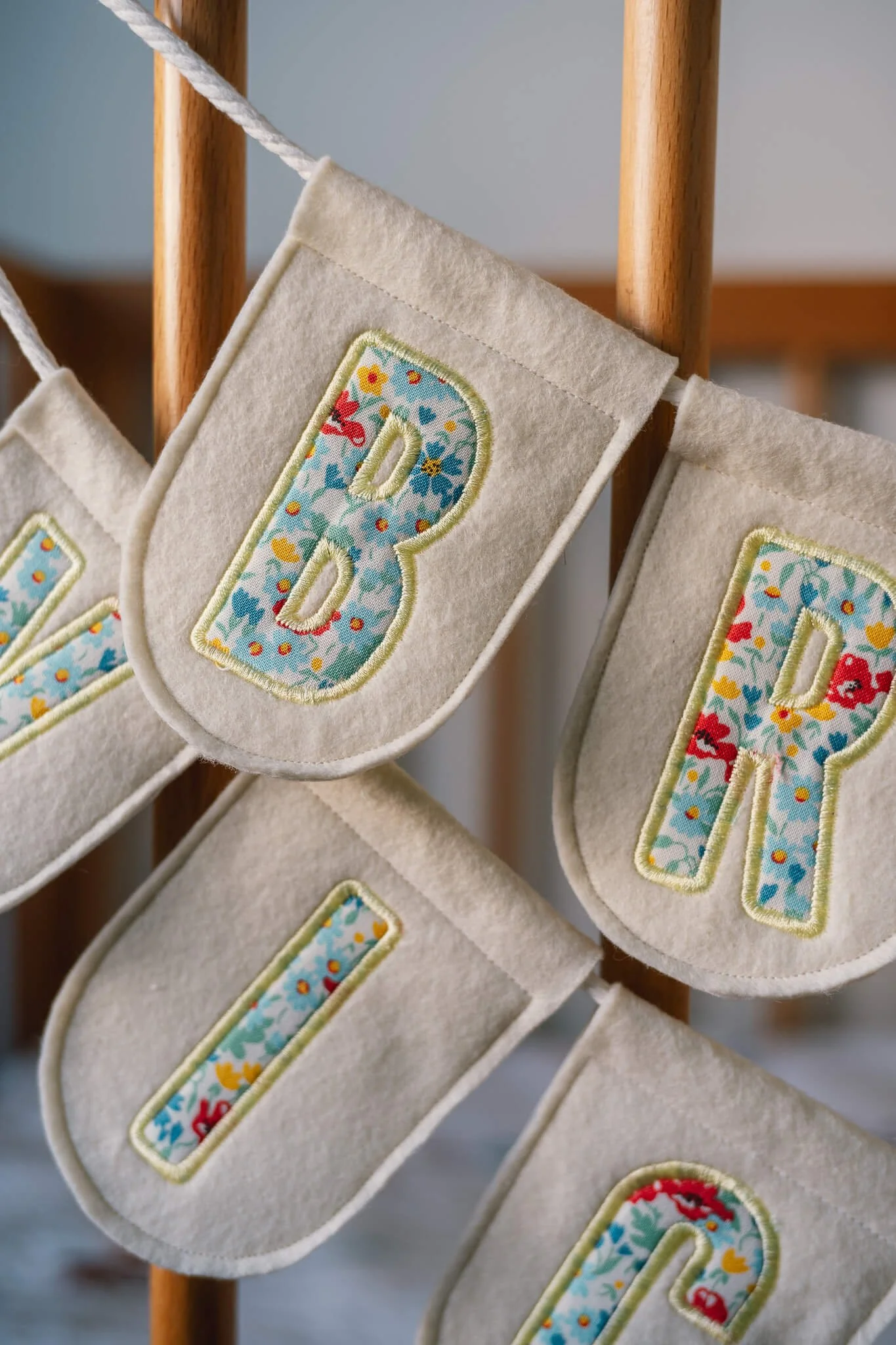 Felt Christmas stockings hanging on a wooden rack, each with colorful fabric applique initials.