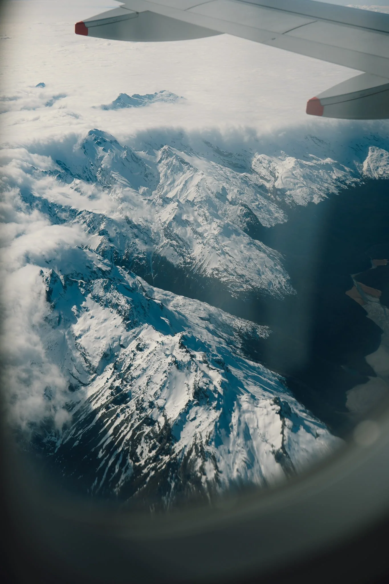View of snow-capped New Zealand mountain ranges from an airplane window on approach to Queenstown