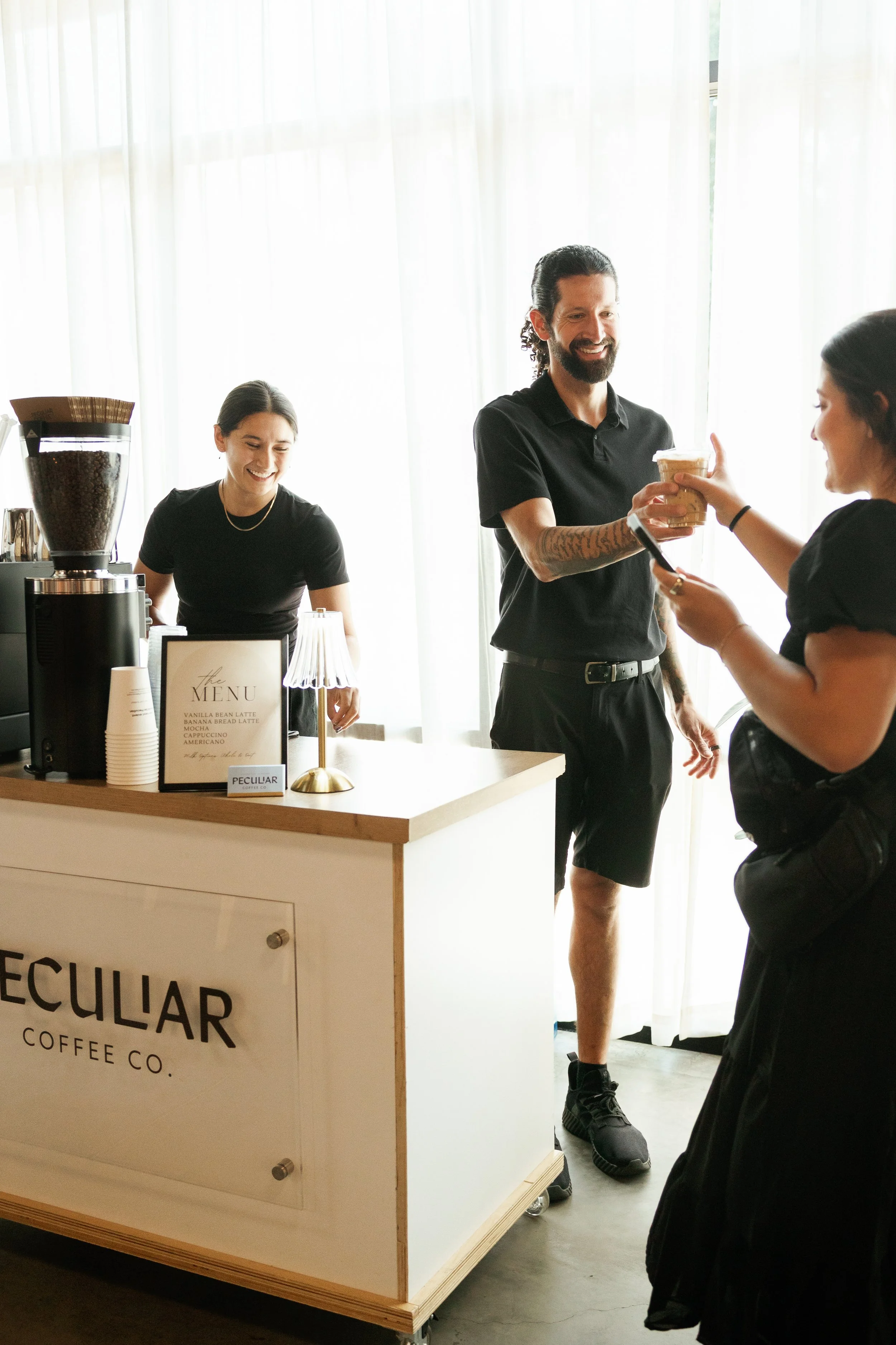 Two smiling people serving coffee at a wedding