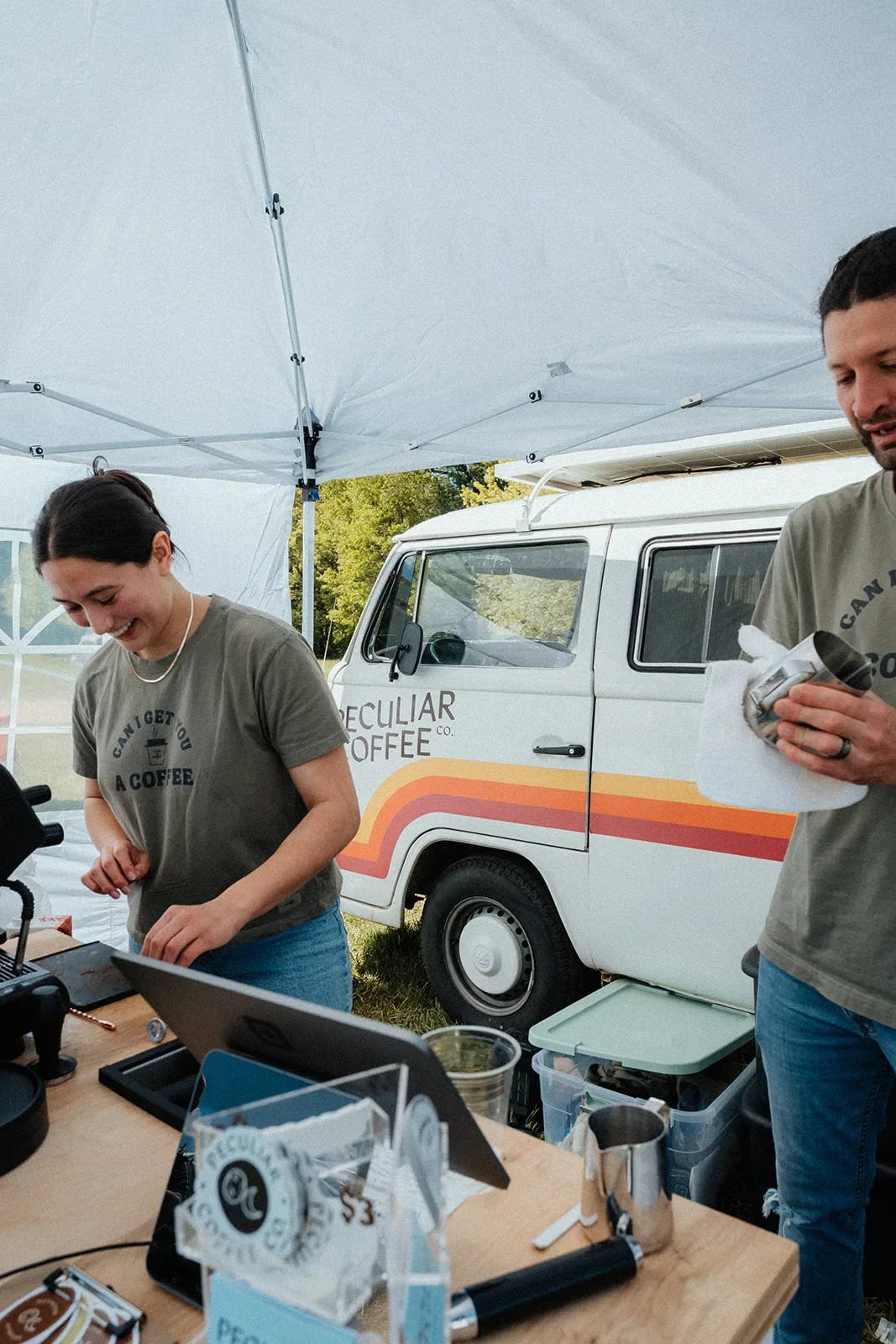Peculiar Coffee baristas taking orders at the cart with the branded Peculiar Coffee Co. van behind them.