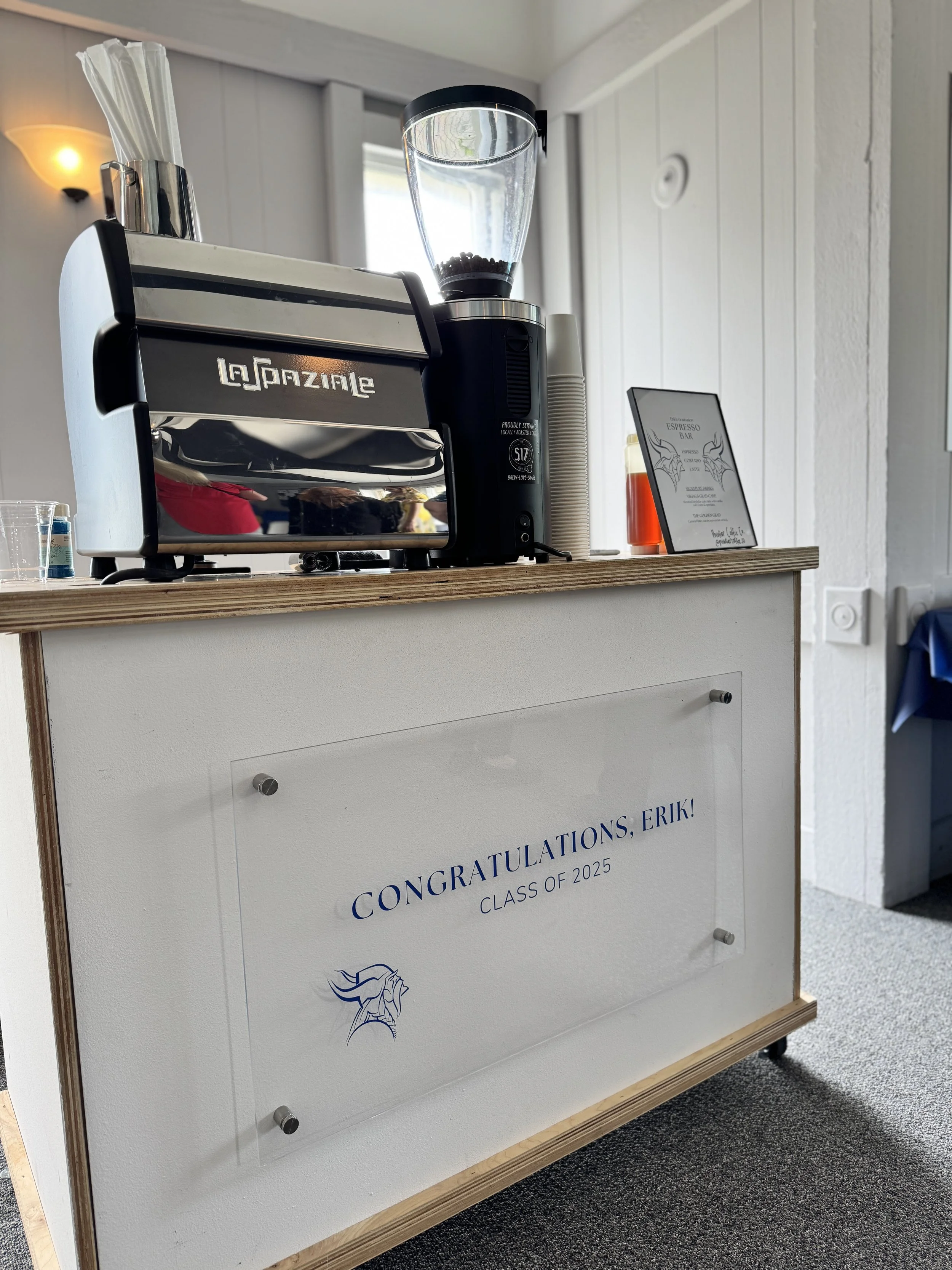 A coffee cart at a graduation party. The custom sign on the front reads "Congratulations, Erik! Class of 2025"