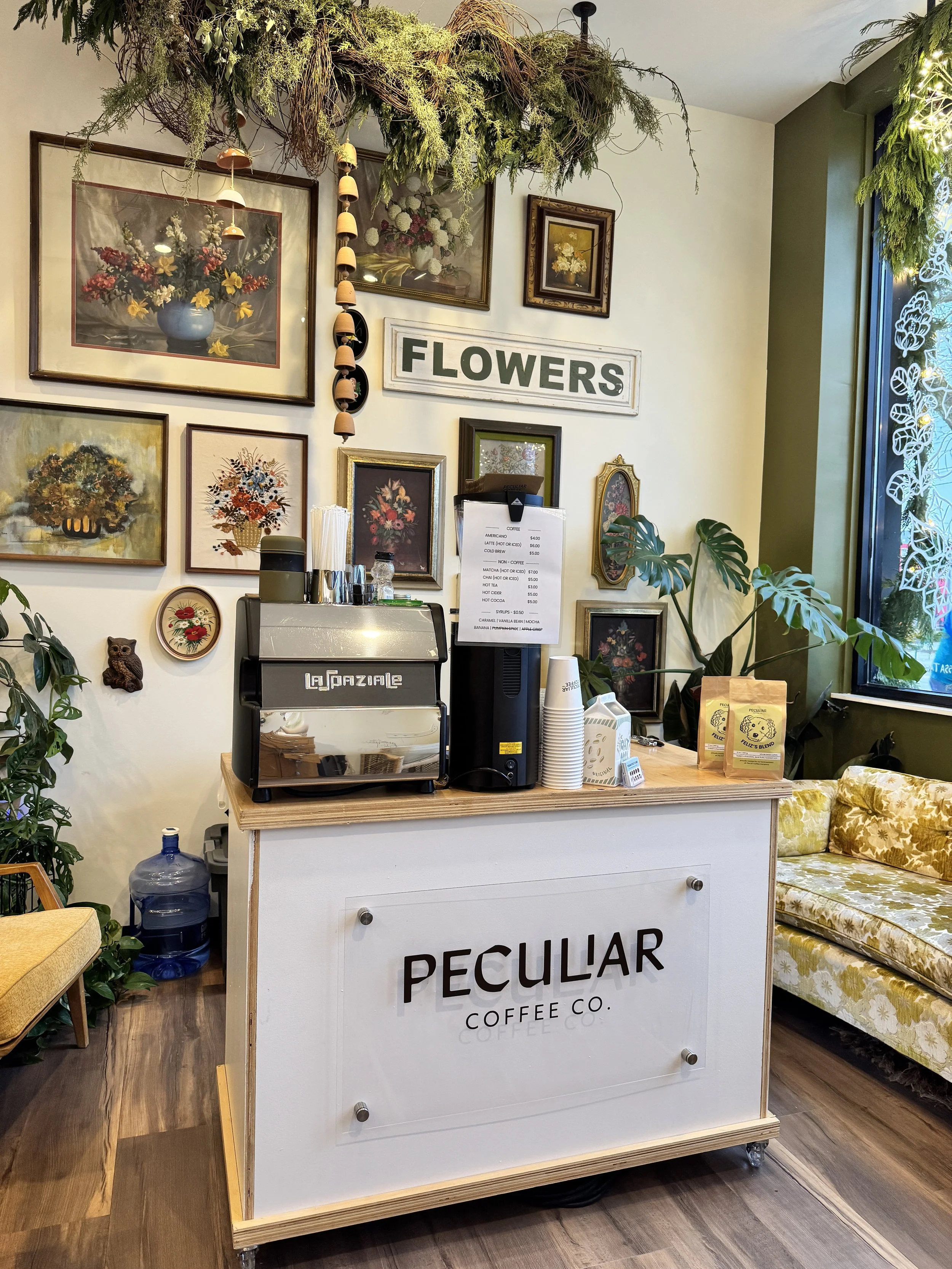 The Peculiar Coffee Co. cart set up in a flower shop, with cups and menu on the counter.