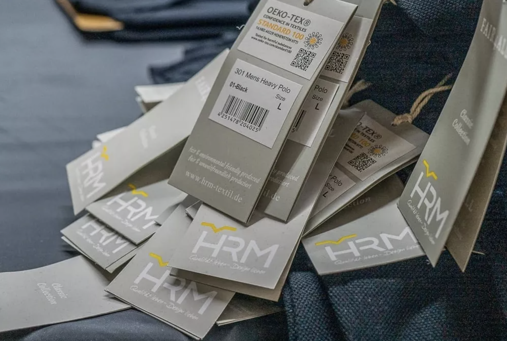 Multiple clothing tags on denim fabric, displaying product information and branding.