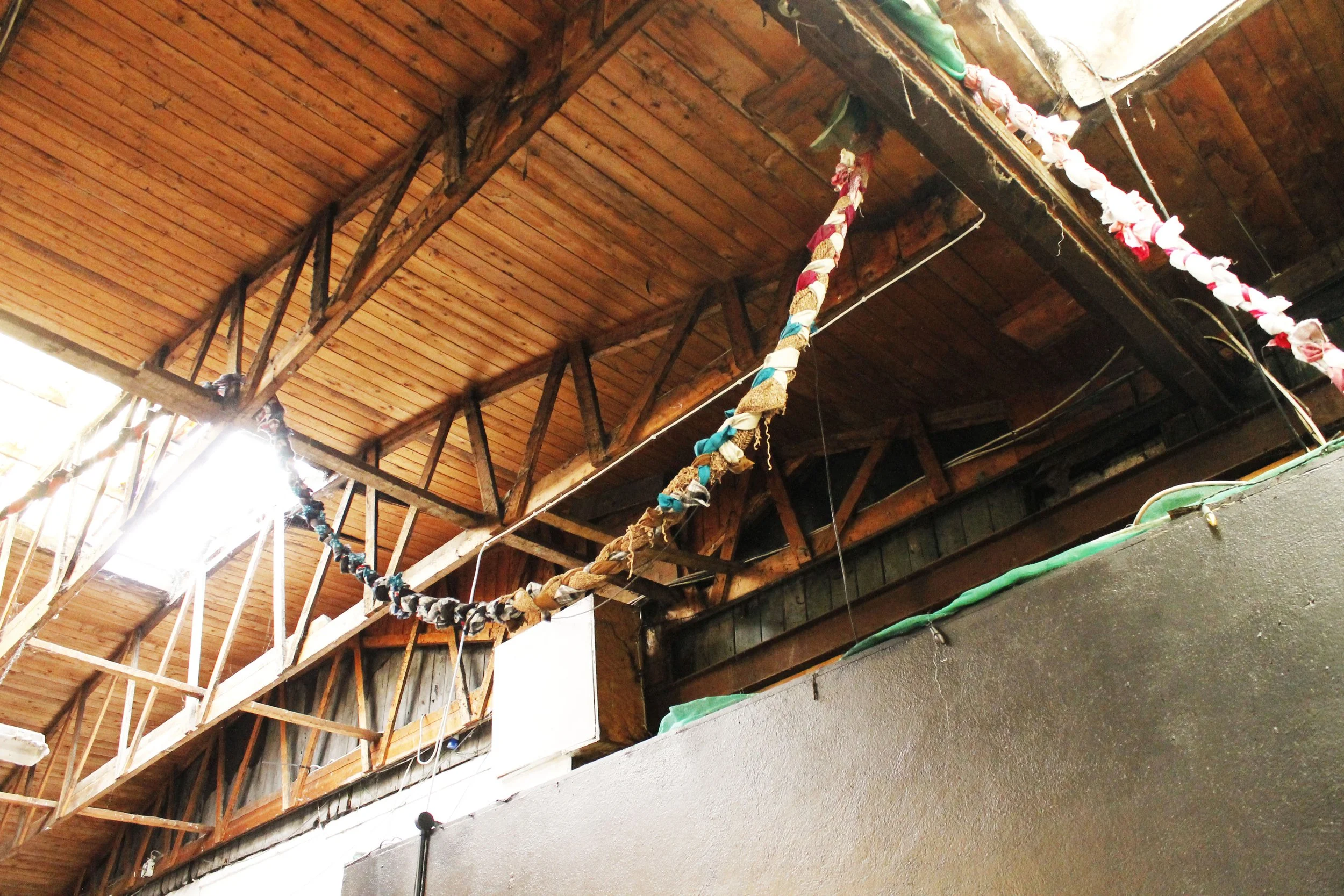 Indoor view of wooden ceiling with decorative fabric garlands hanging.