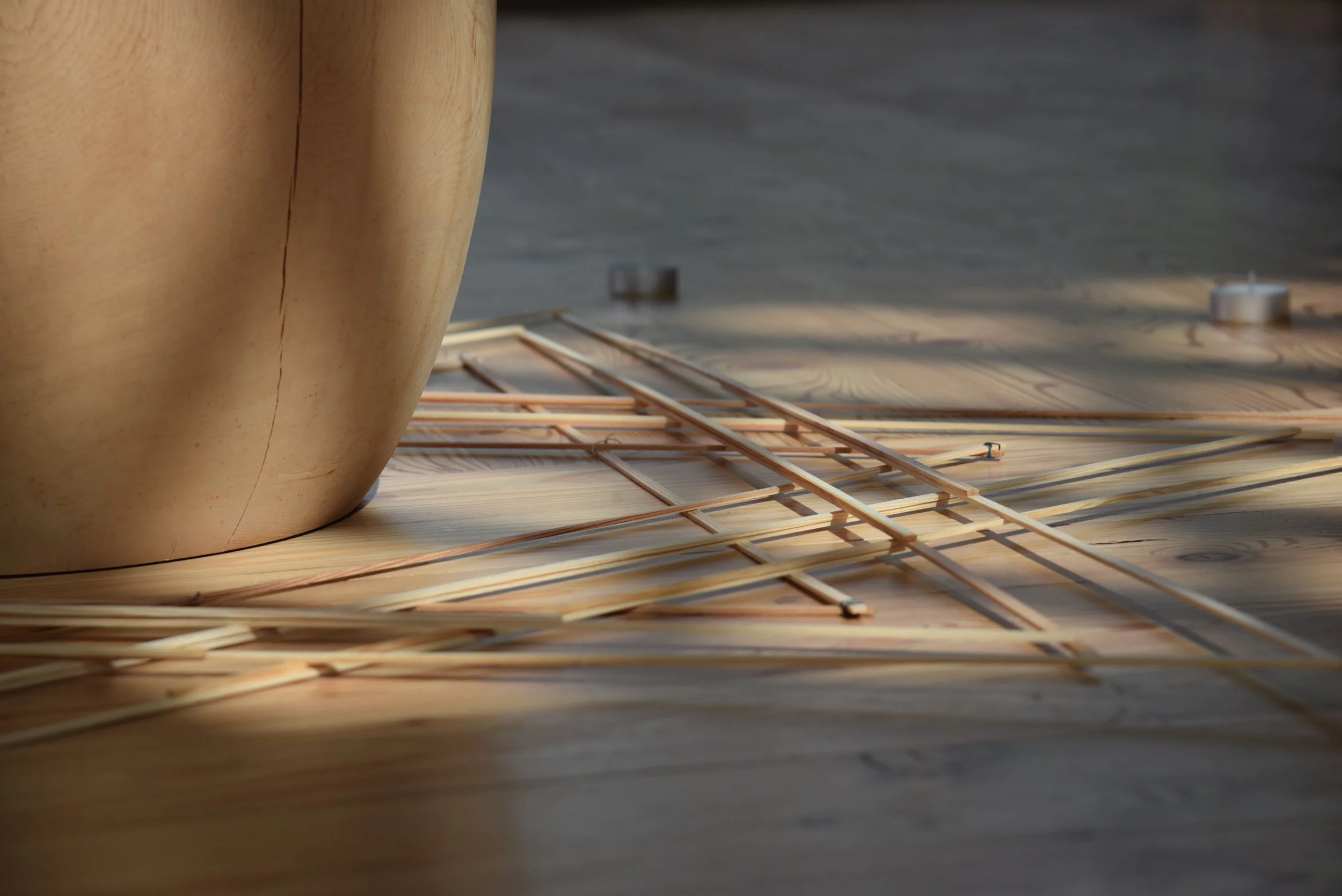 Nahaufnahme eines Holzrobos mit Spagat, mit Holzstäben und kleinen Kerzen im Hintergrund auf einem Holztisch.