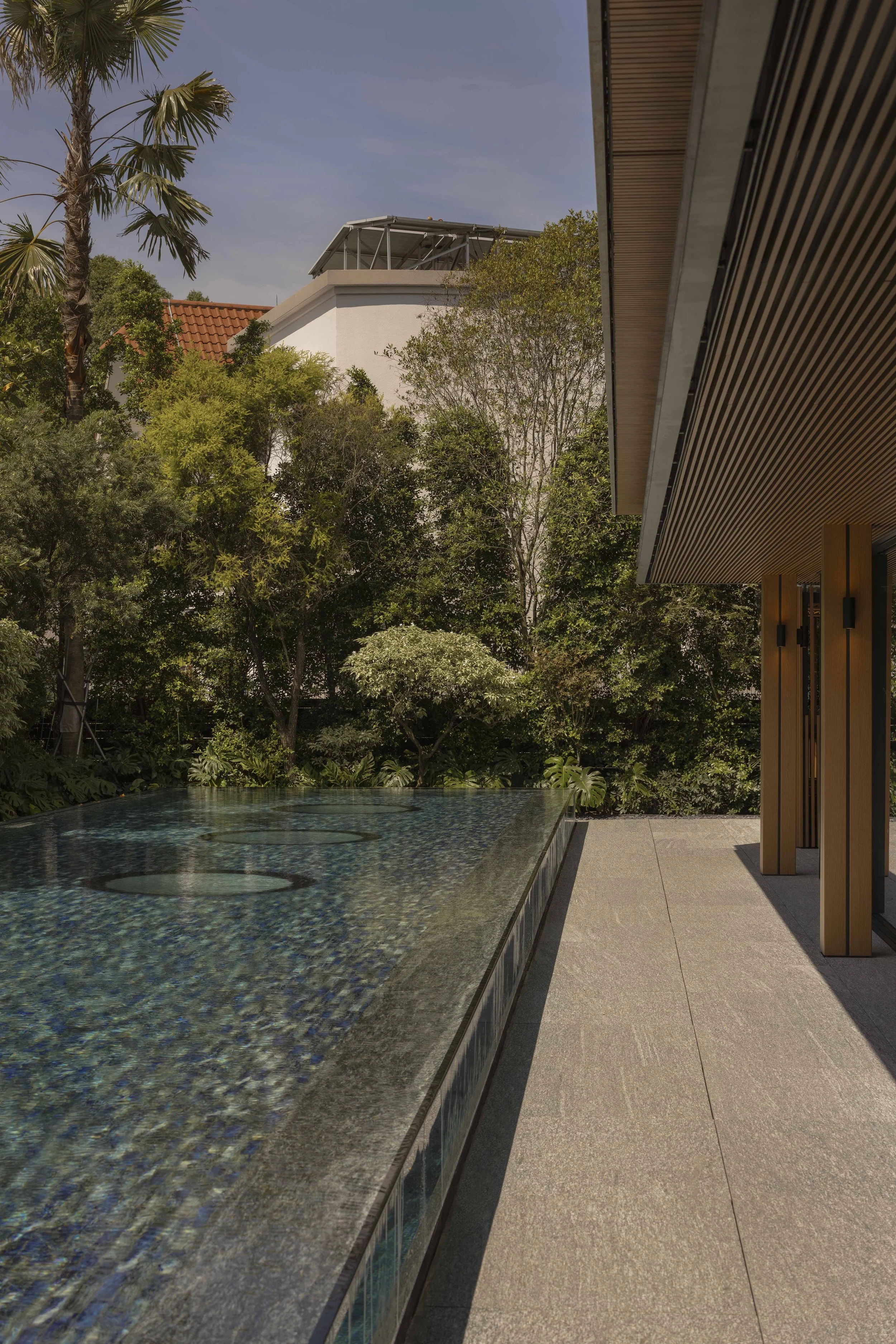 A swimming pool by the side of a house with 3 skylights at the bottom of the pool
