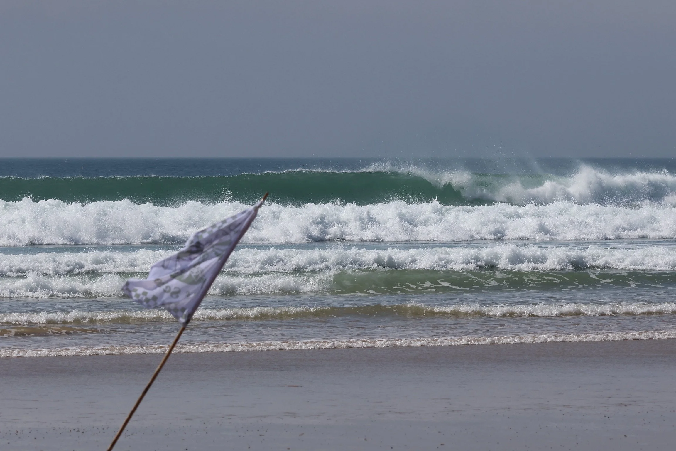 Vague  avec un drapeau de plage dans le premier plan sur la plage.