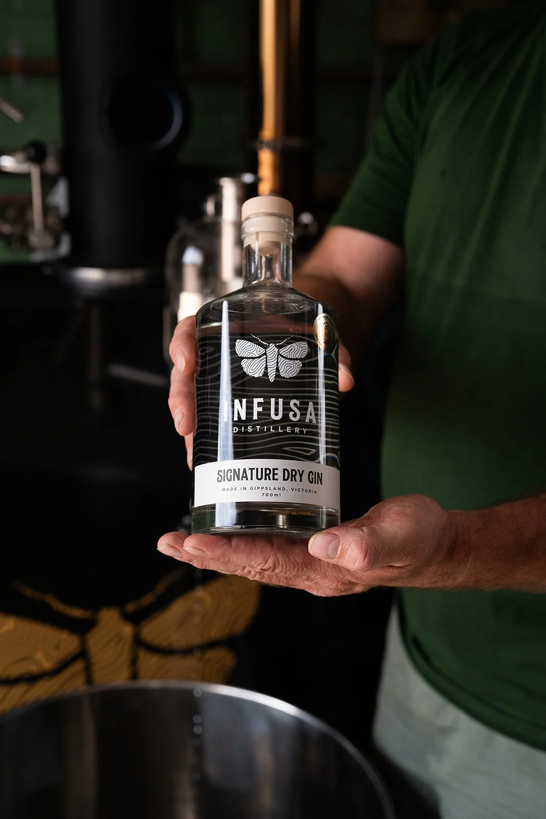 Person holding a bottle of Infusa distillery signature dry gin.