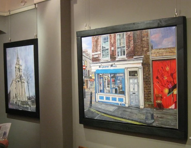 Painting of a street scene featuring a blue shopfront, brick building, and red graffiti wall.