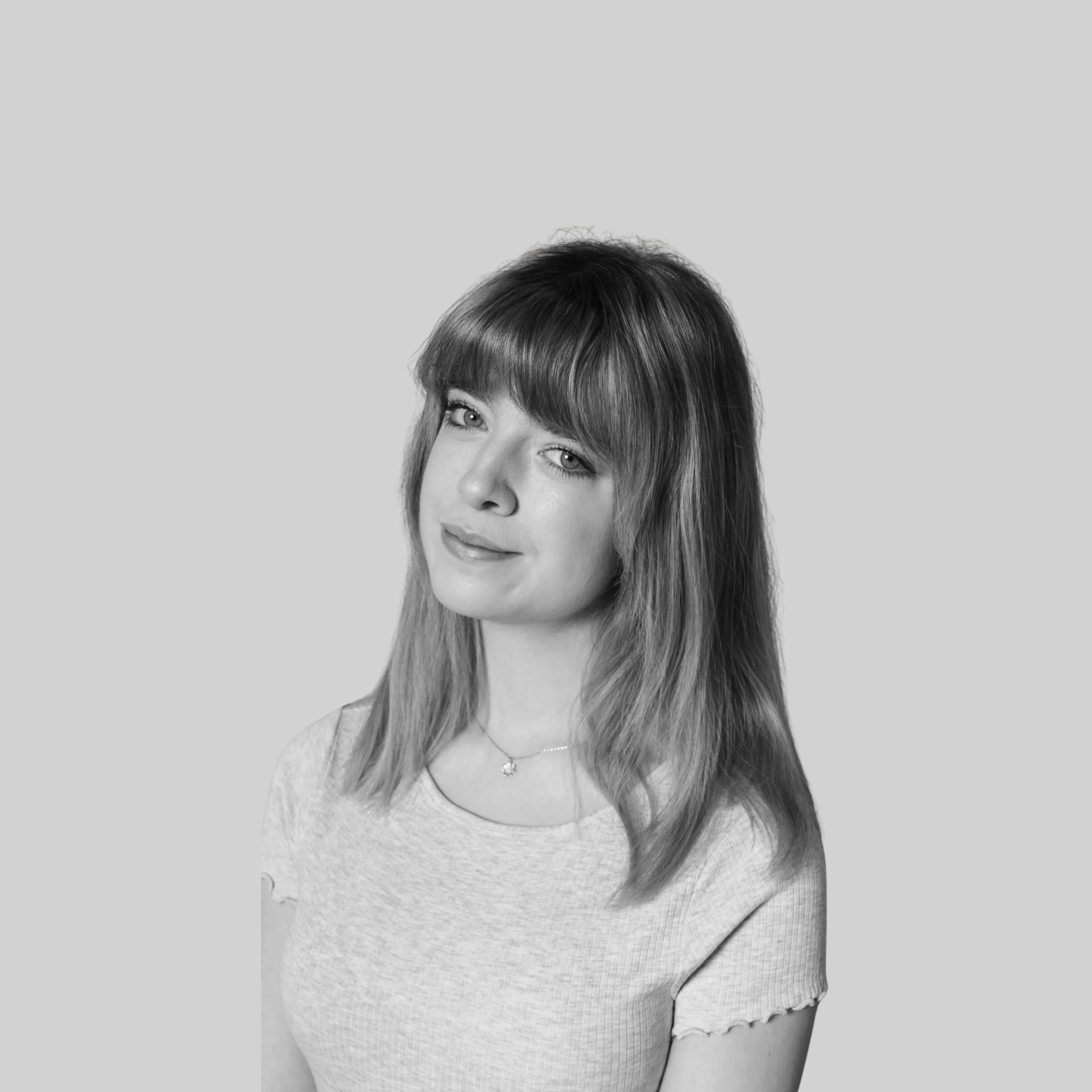 Neve Hutchinson has long hair and a fringe. She is also wearing a necklace.