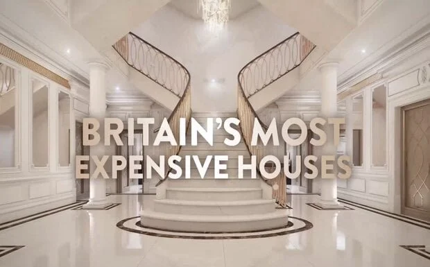 A bright shining white staircase sweeps into a foyer. There is a chandelier above. The text 'Britain's Most Expensive Houses' is is white text.