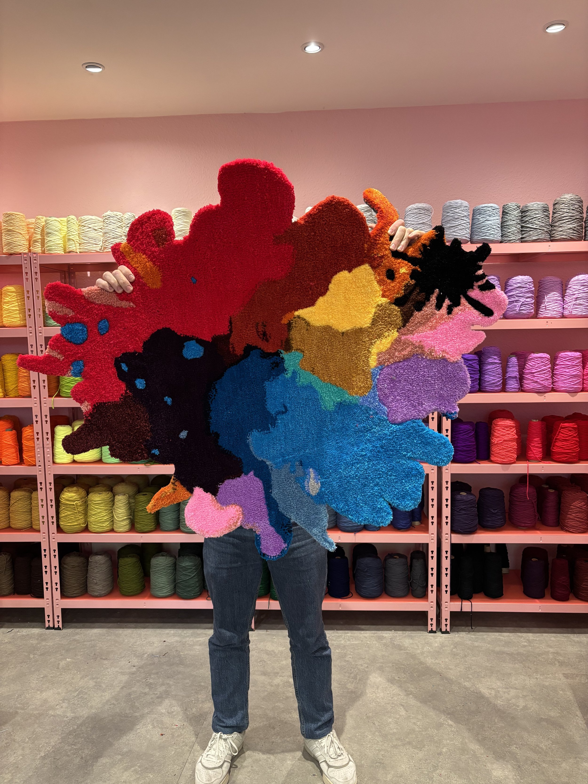 A handcrafted paint splash rug is being held up