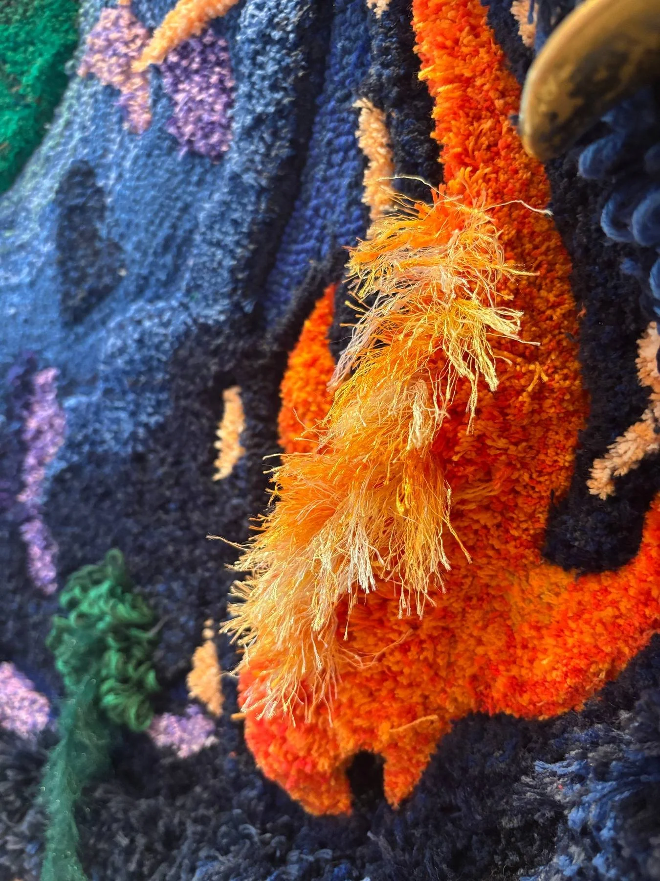 A navy 3D tufted rug with an orange fish at the top and a green leaf below, with small flowers.(The 3D One)