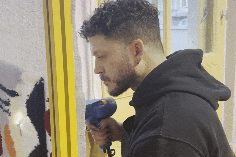 A tufting workshop in progress. A man at a corporate team building event holds a tufting gun