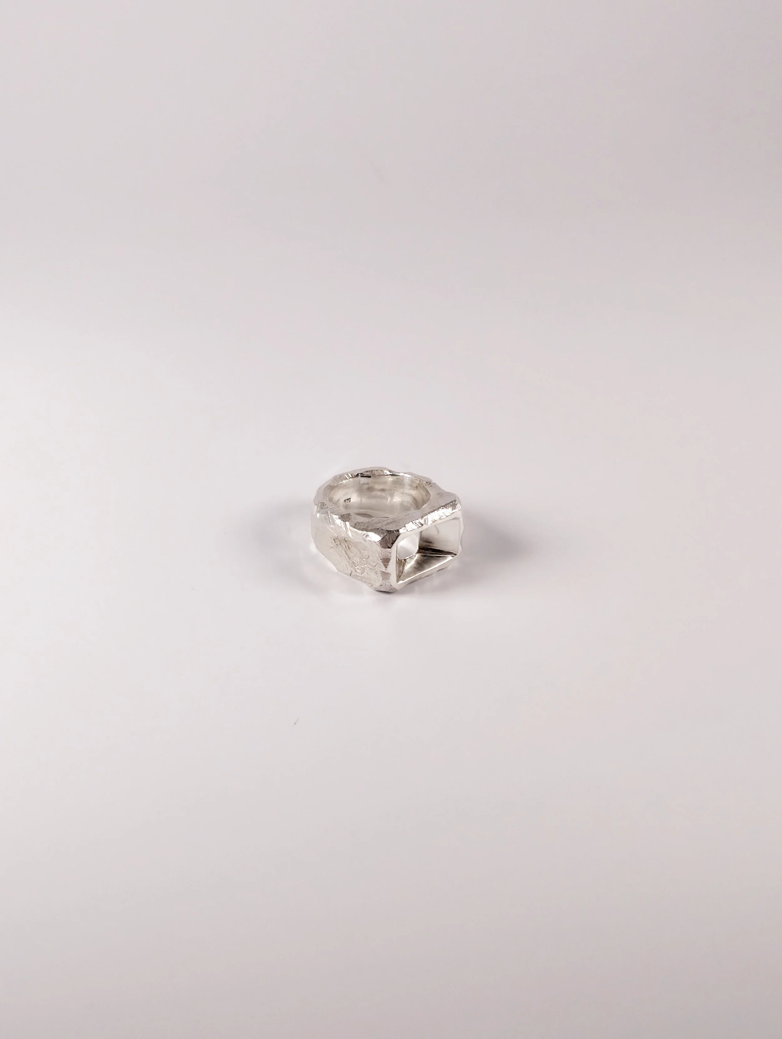 Polished silver ring with a raised geometric block pattern, side view