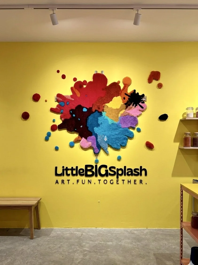 A custom rug with the logo LITTLE BIG SPLASH stands against a yellow wall