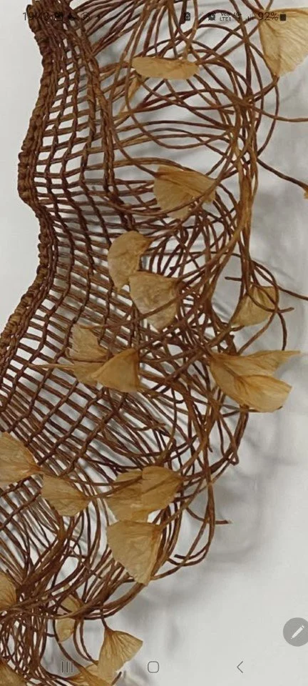 Structure en rotin décorée de feuilles séchées.