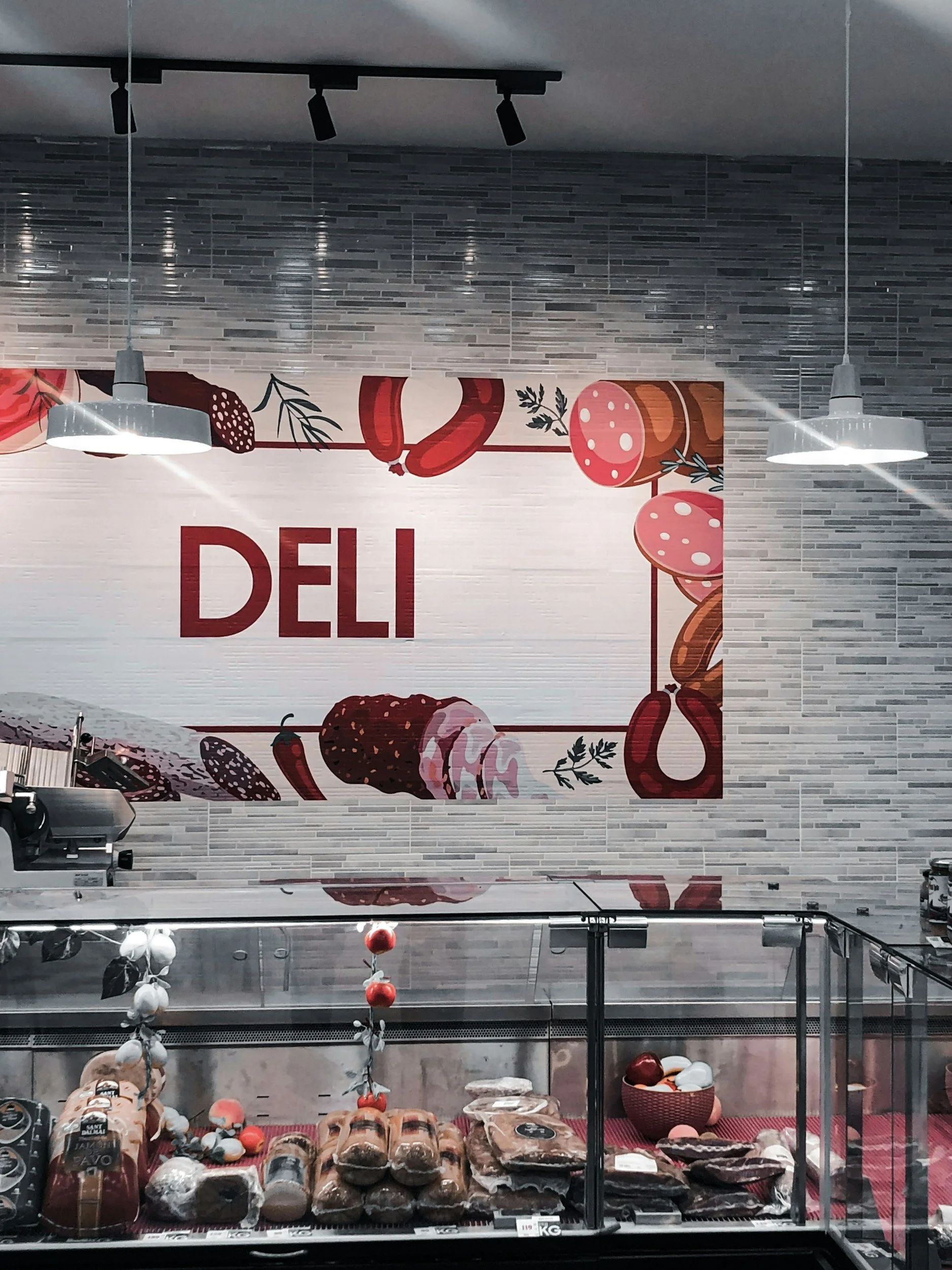 Frozen supermarket display with meats, sausages, and deli items, decorated with red and white holiday ornaments and a large sign with partial word 'DEL' visible.