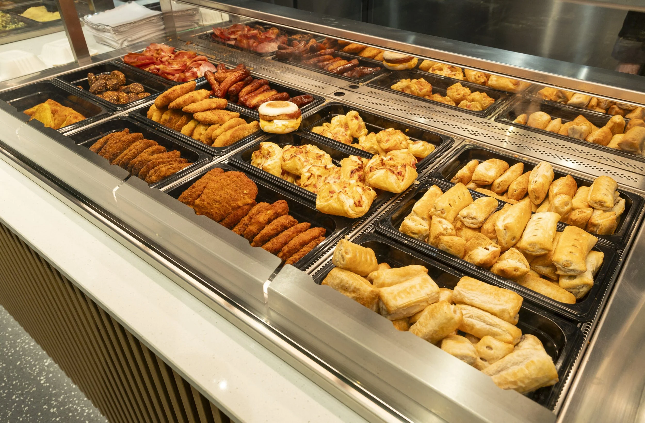 Display case filled with various fried foods and baked pastries.